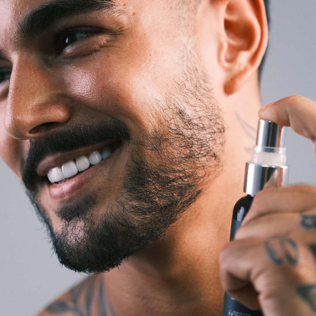 Homem sorrindo aplicando o tônico Fórmula X na barba