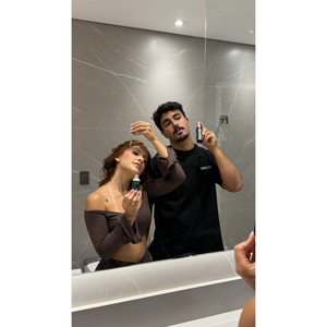 Casal aplicando Fórmula X e Fórmula Y no espelho do banheiro
