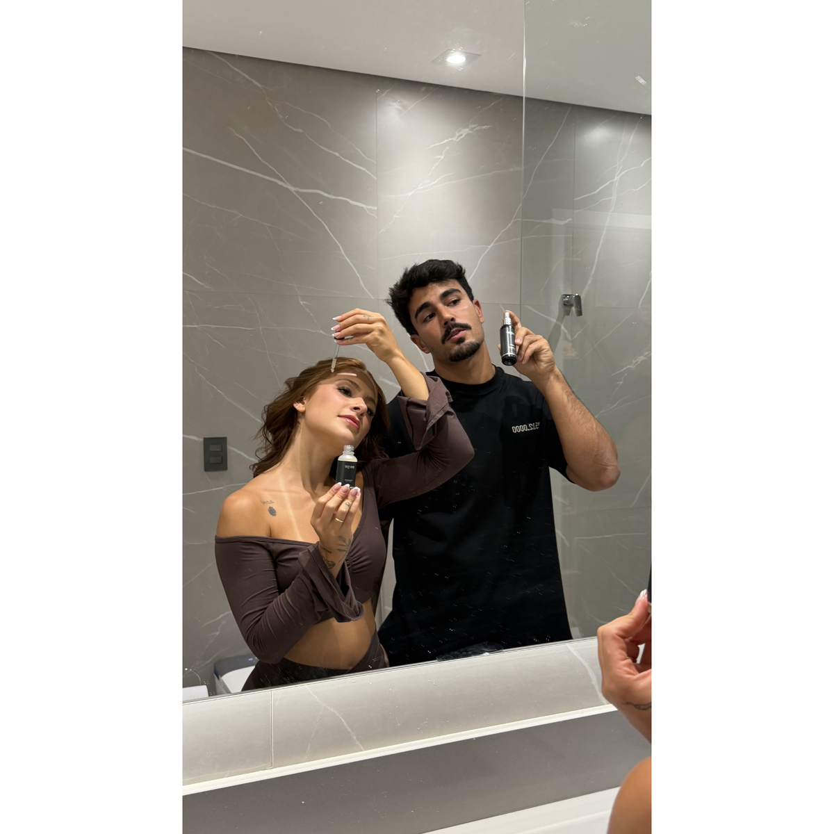 Casal aplicando Fórmula X e Fórmula Y no espelho do banheiro